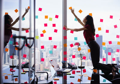 Woman sticking adhesive notes on glass window