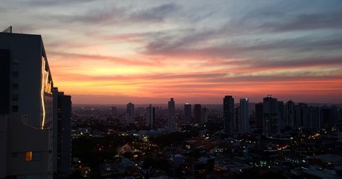 Illuminated buildings in city against sky during sunset