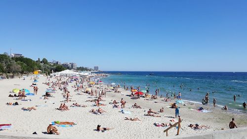 Group of people on beach against clear sky