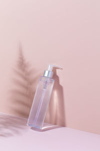 A mock-up of a cosmetic product on a pink background with fern shadows. cleansing tonic 