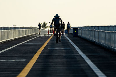 Rear view of woman walking on road against clear sky