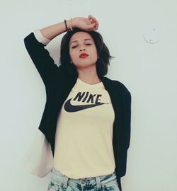 Portrait of young woman standing against wall