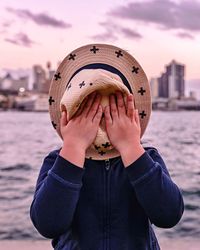 Close-up of boy with hat by sea