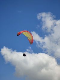 Low angle view of person paragliding against sky