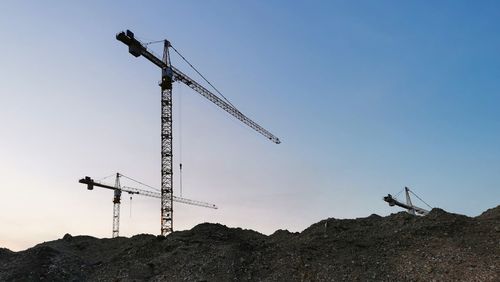 Low angle view of crane at construction site against clear sky