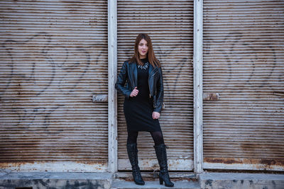 Portrait of young woman standing against closed shutter