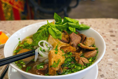 Pho bo or vietnamese soup with beef and meat balls served in a white bowl at the restaurant. 