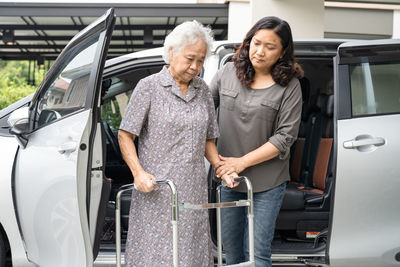 Caregiver help and support asian senior woman patient walk with walker prepare get to her car.