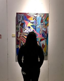 Rear view of woman standing against multi colored wall