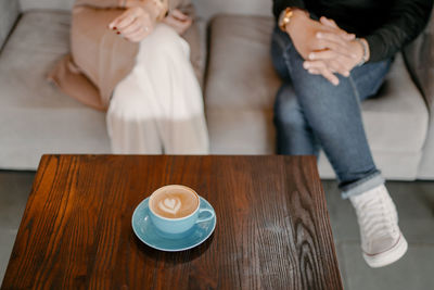 Midsection of woman with coffee cup on table