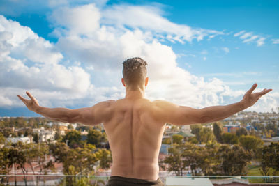 Rear view of shirtless man standing against sky