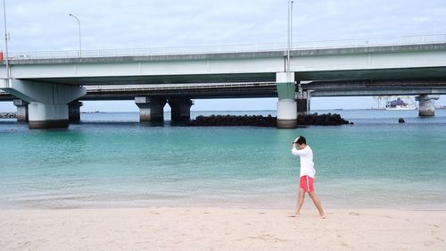 Full length of woman standing on beach against sky