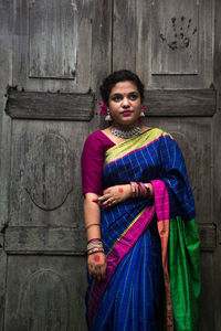 Portrait of young woman standing against wall