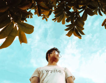 Low angle view of young man looking away against sky