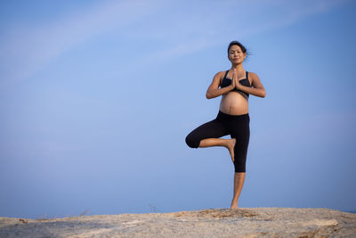 Full length of woman standing against blue sky