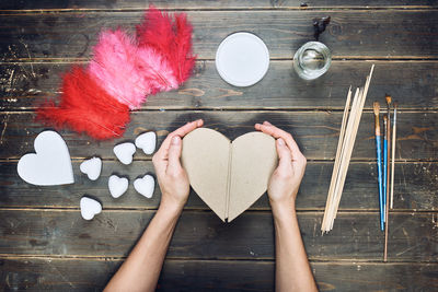 Directly above shot of woman hand holding heart shape on table