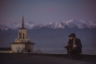 Man sitting against snowcapped mountain during sunset