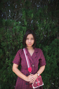 Portrait of beautiful woman standing by tree