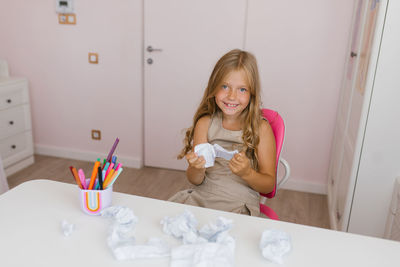 Caucasian schoolgirl is sitting on a chair at a table with a torn page from a school notebook 