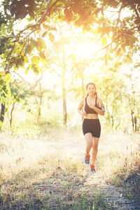 Full length of determined woman jogging on dirt road in forest