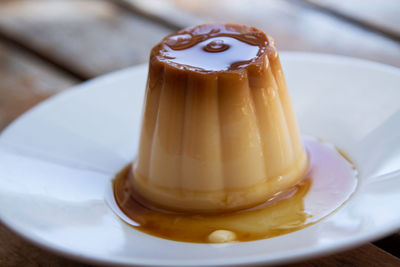 White plate with flan on wooden background, close up view