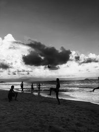 People playing on beach against sky