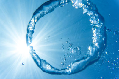 Close-up of bubbles in water against blue sky