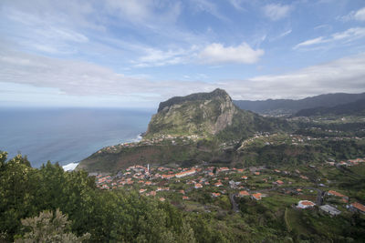 Scenic view of sea by townscape against sky