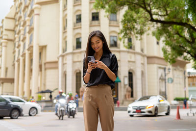 Full length of woman using mobile phone on street