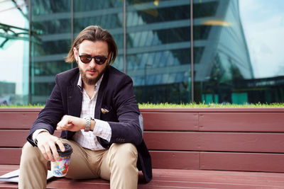 Businessman checking time while sitting on bench