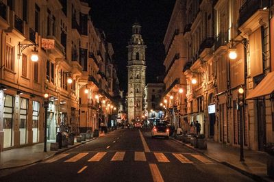 Empty road amidst buildings in city at night