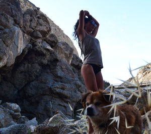 Woman with dog standing on rock against clear sky