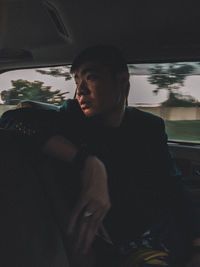 Young man looking through camera while sitting in car