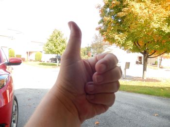 Close-up of hand holding hands against sky