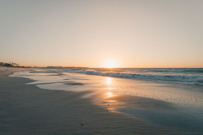 Scenic view of beach against clear sky during sunset