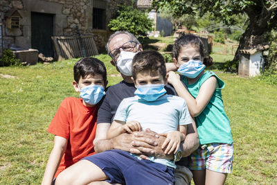 Portrait of grandfather with grandchildren wearing masks in yard