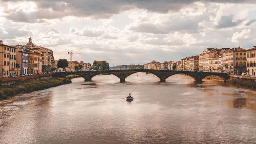 Arch bridge over river against buildings in city