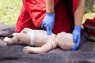 Midsection of paramedic performing cpr on dummy