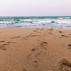 Footprints on sand at beach against sky