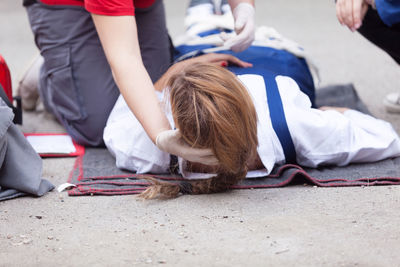 Low section of paramedic treating female patient on field