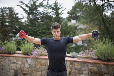 Full length of man with arms outstretched standing against plants