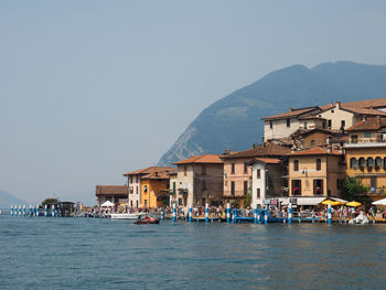 Buildings by sea against clear sky