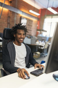 Portrait of a smiling young man sitting on table