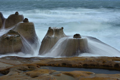 Scenic view of waterfall by sea