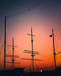 Low angle view of silhouette ships against orange sky