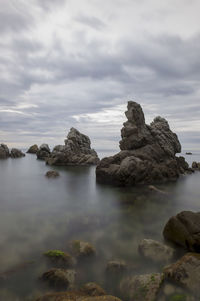 Rocks on sea shore against sky