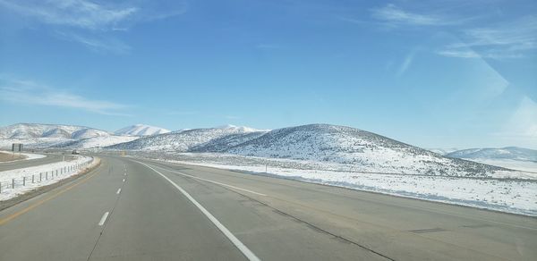 Road by snowcapped mountains against sky