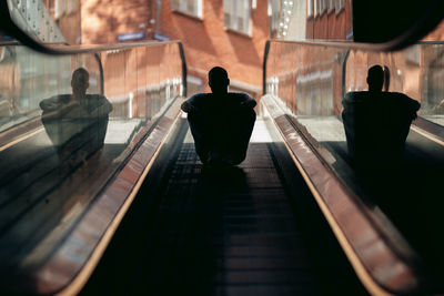 Rear view of man walking on escalator