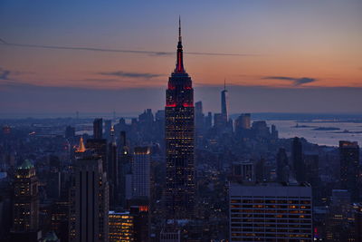 Illuminated empire state building in city against sky during sunset