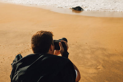 Rear view of man photographing beach